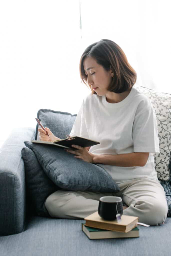 woman sitting on a couch writing in a journal